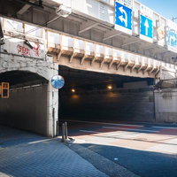 南池袋のびっくりガード入口と道路標識、高架橋下の街並みの写真