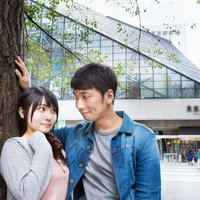 周囲の目を気にせず木ドンをする休日のカップルの写真