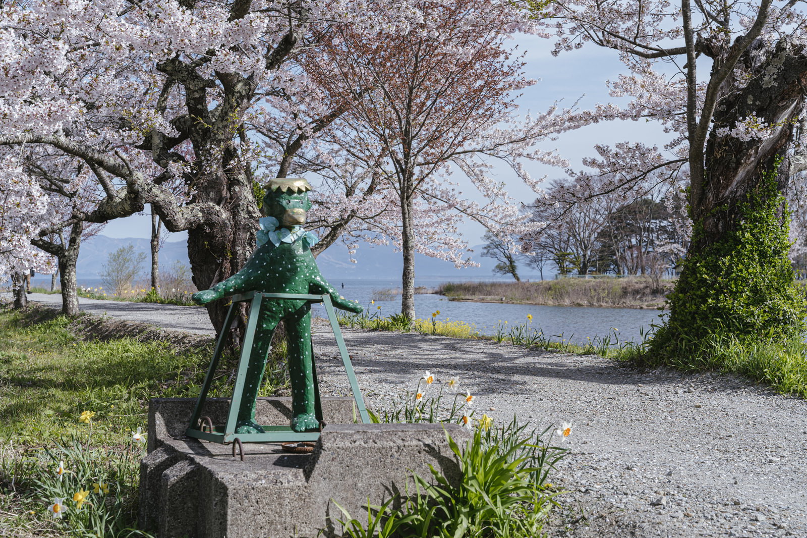 満開の桜並木の下にある船津川の河童の像「がたろ」