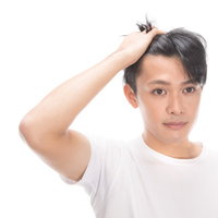 生え際をチェックする若い男性の写真