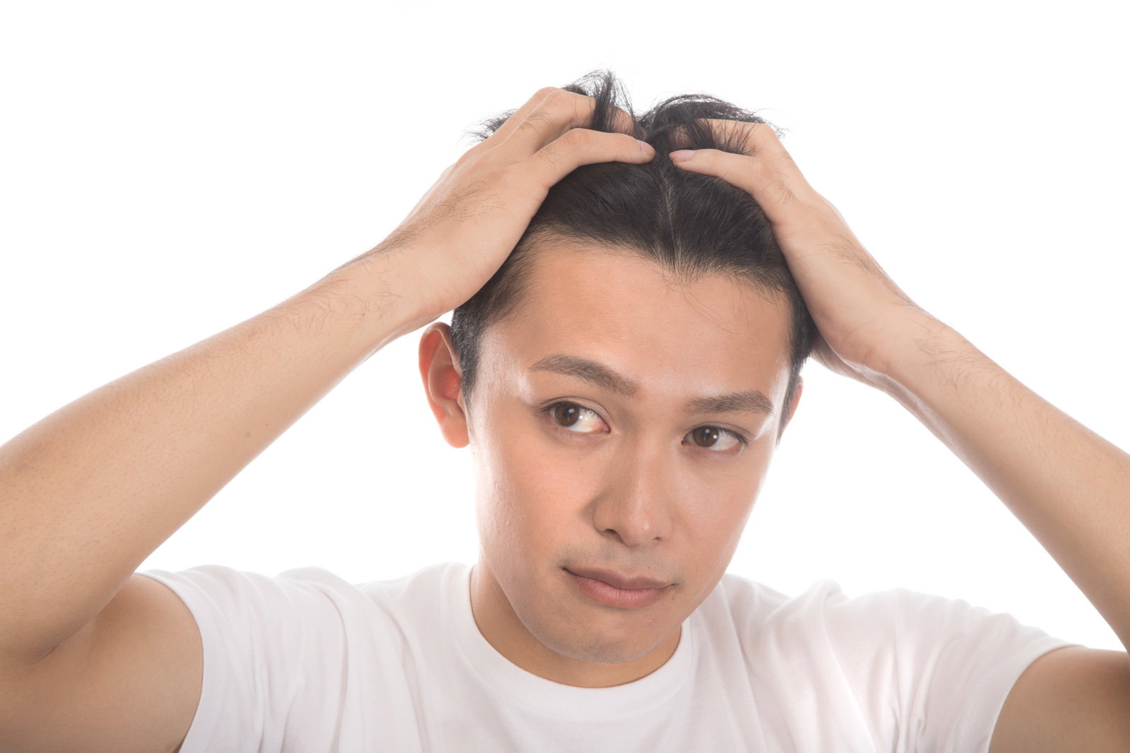 両手で頭を抱えながら生え際を確認している若い男性［モデル：完伍］