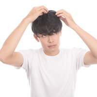 頭髪を気にする若い男性が鏡の前で自分を見つめるの写真