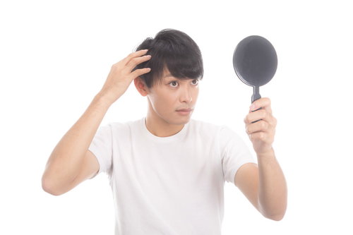 手鏡で薄毛・生え際のヘアチェックをする若い男性