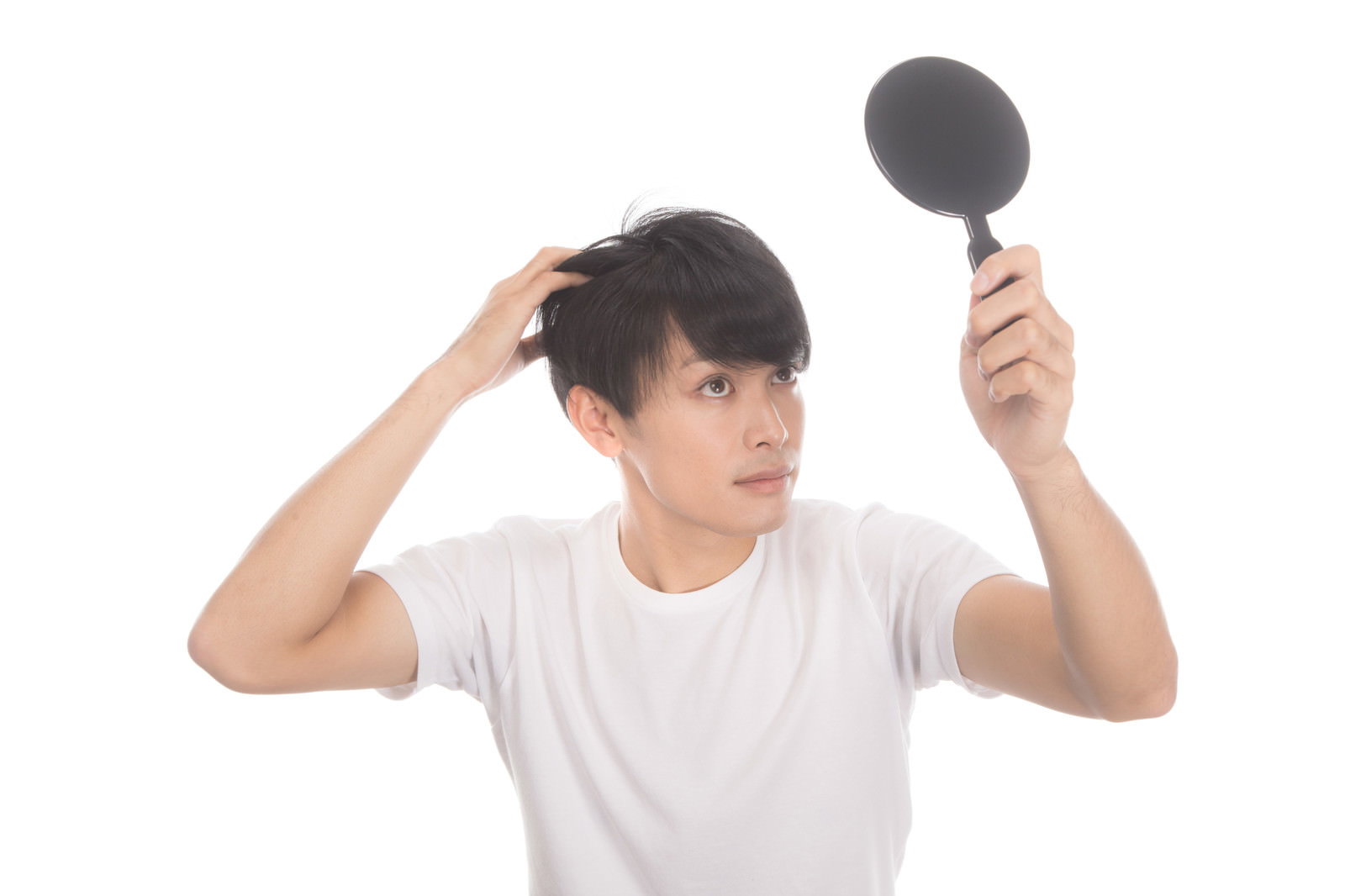 手鏡で髪をチェックする白いTシャツの男性［モデル：完伍］