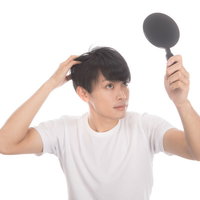 若ハゲ予防に手鏡でヘアチェックする男性の薄毛セルフチェックの写真