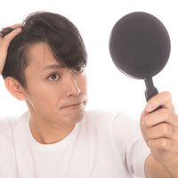 鏡を見るたびに生え際が気になる若い男性の髪の悩みの写真