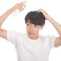 育毛剤スプレーを頭部に使う男性のAGA対策ヘアケアの写真
