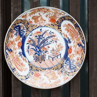 古い木材の壁に取り付けられた伊万里焼の青と赤茶色の装飾皿の写真