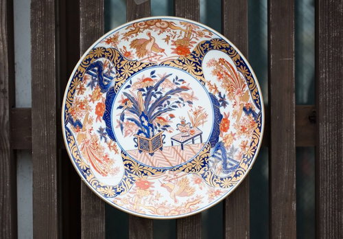 古い木材の壁に取り付けられた伊万里焼の青と赤茶色の装飾皿