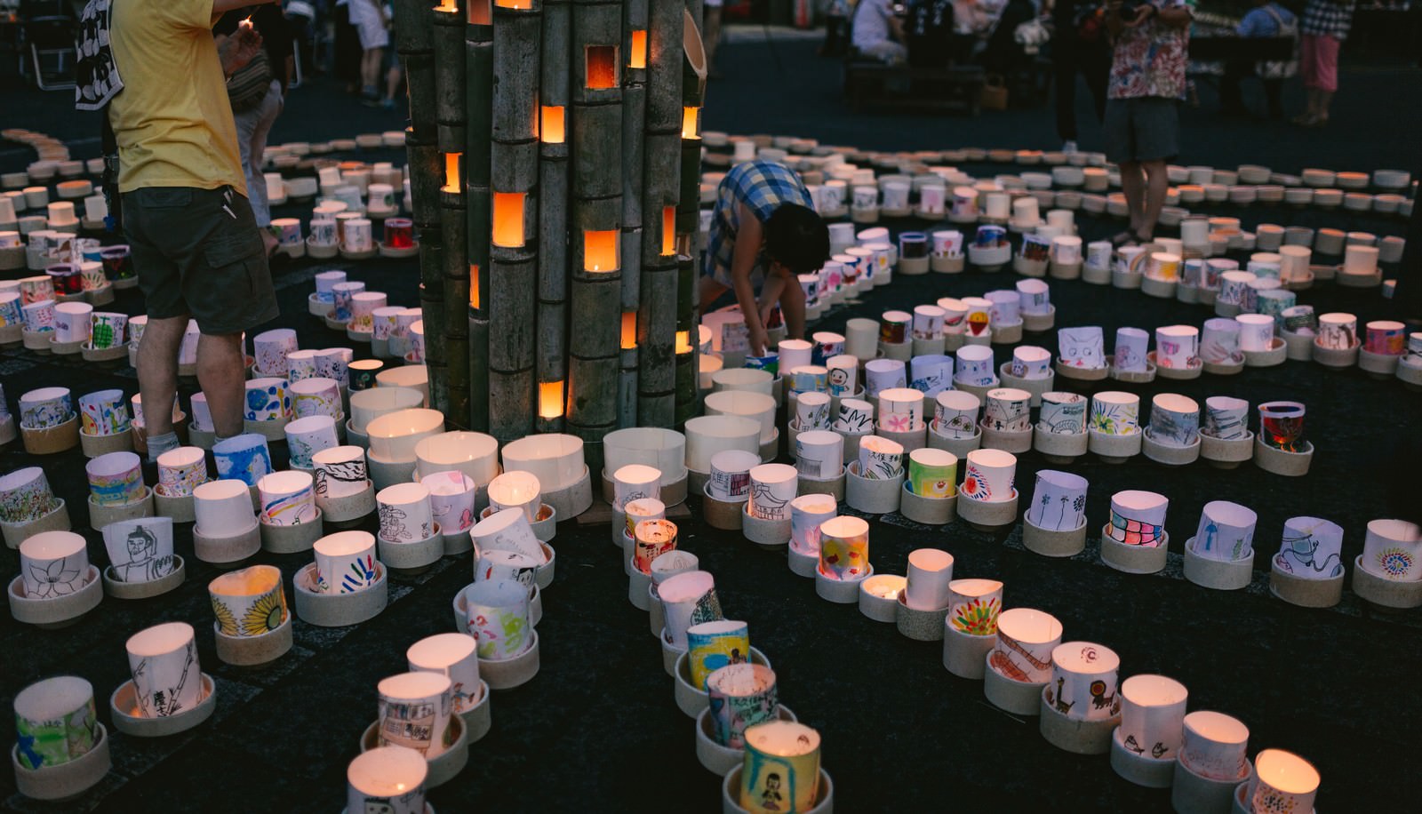 夕暮れの空の下、石段や通路に無数の灯ろうが並んで点灯している光景