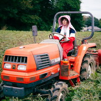 さつまいも畑でトラクターを運転する女性農家の写真