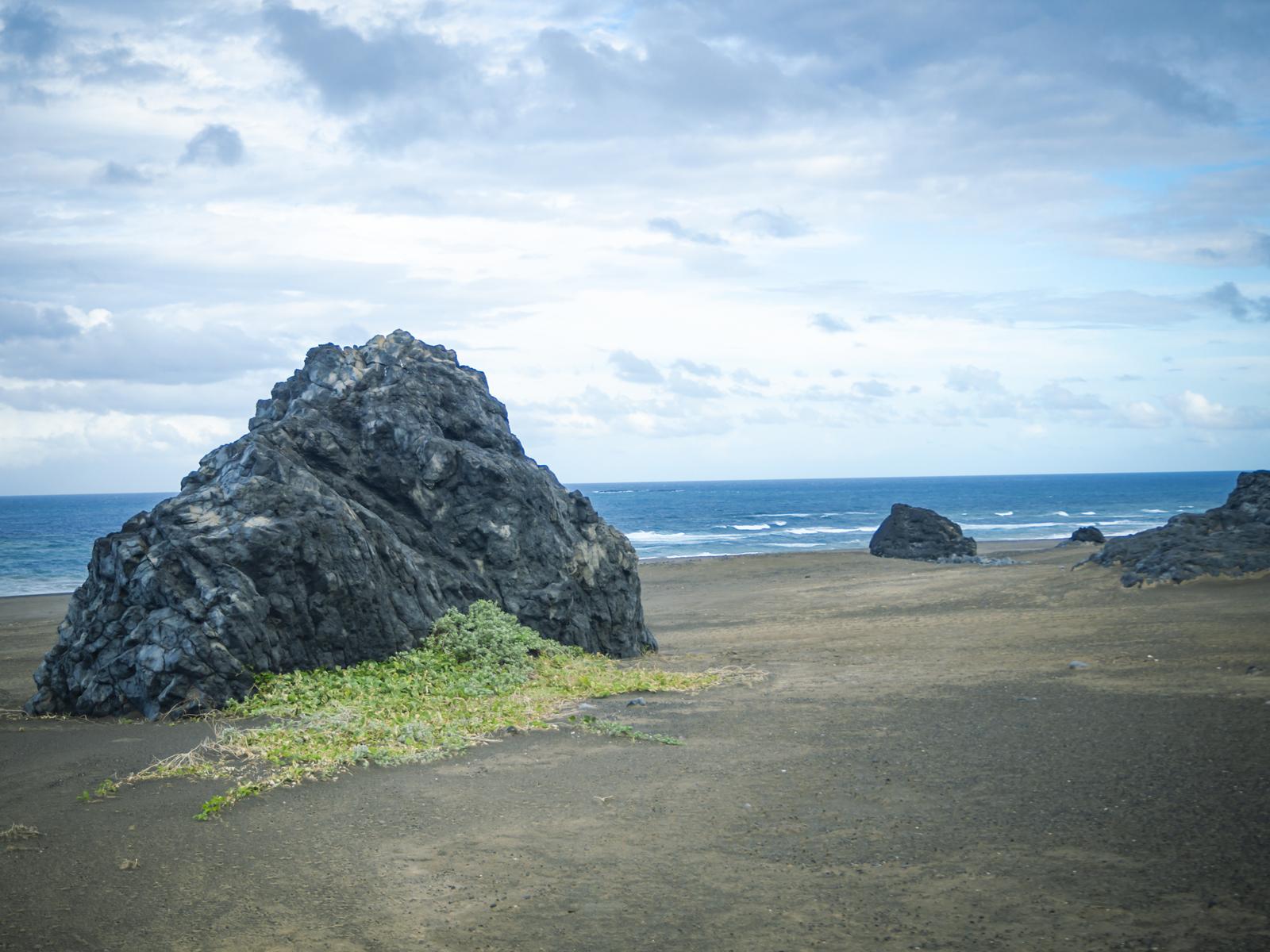 硫黄島の黒い砂浜に露出した火山岩と水平線