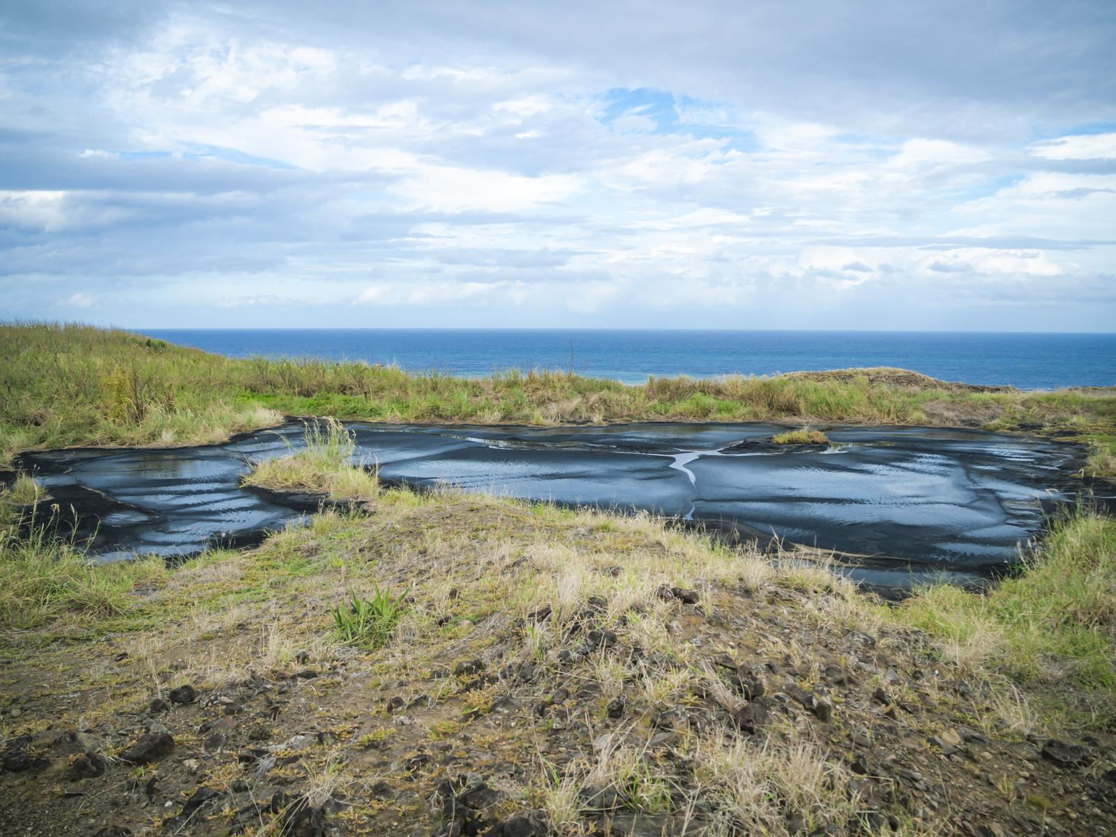 硫黄島の米軍廃棄タールの池と海岸線、黄緑の草地に囲まれた風景