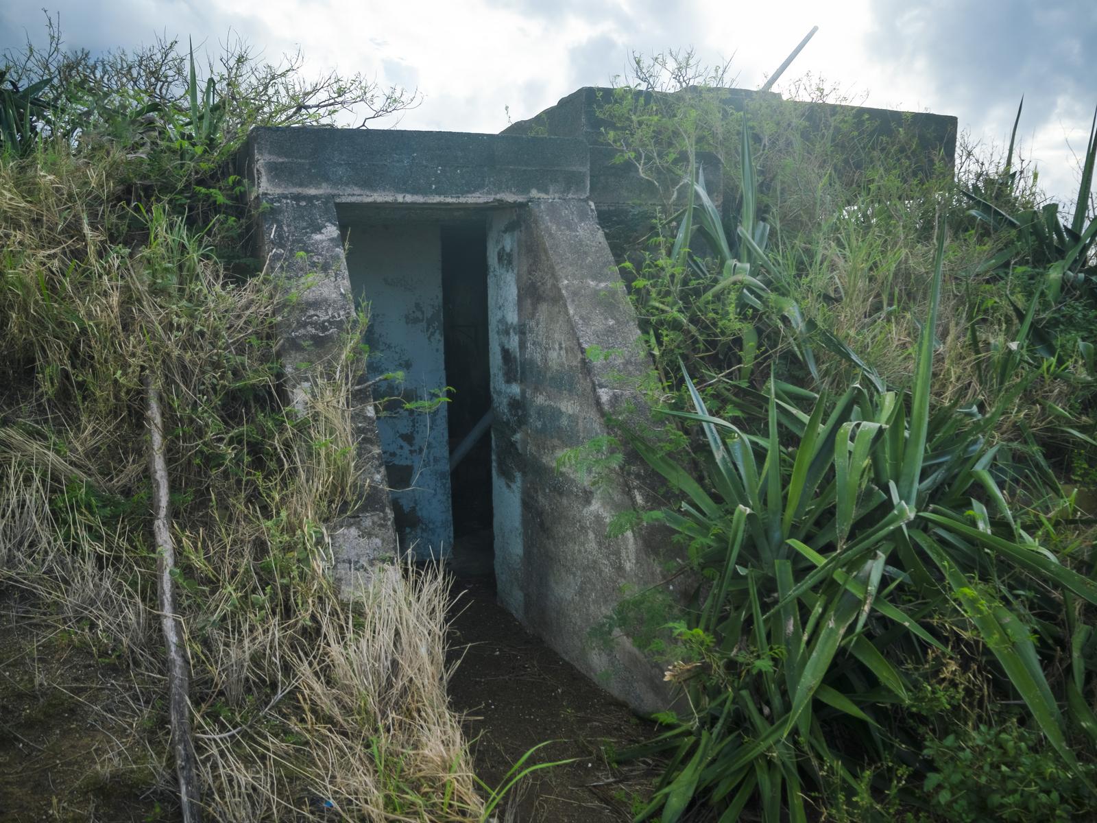 硫黄島の米軍IWOパブ入口。雑草に囲まれたコンクリート建造物