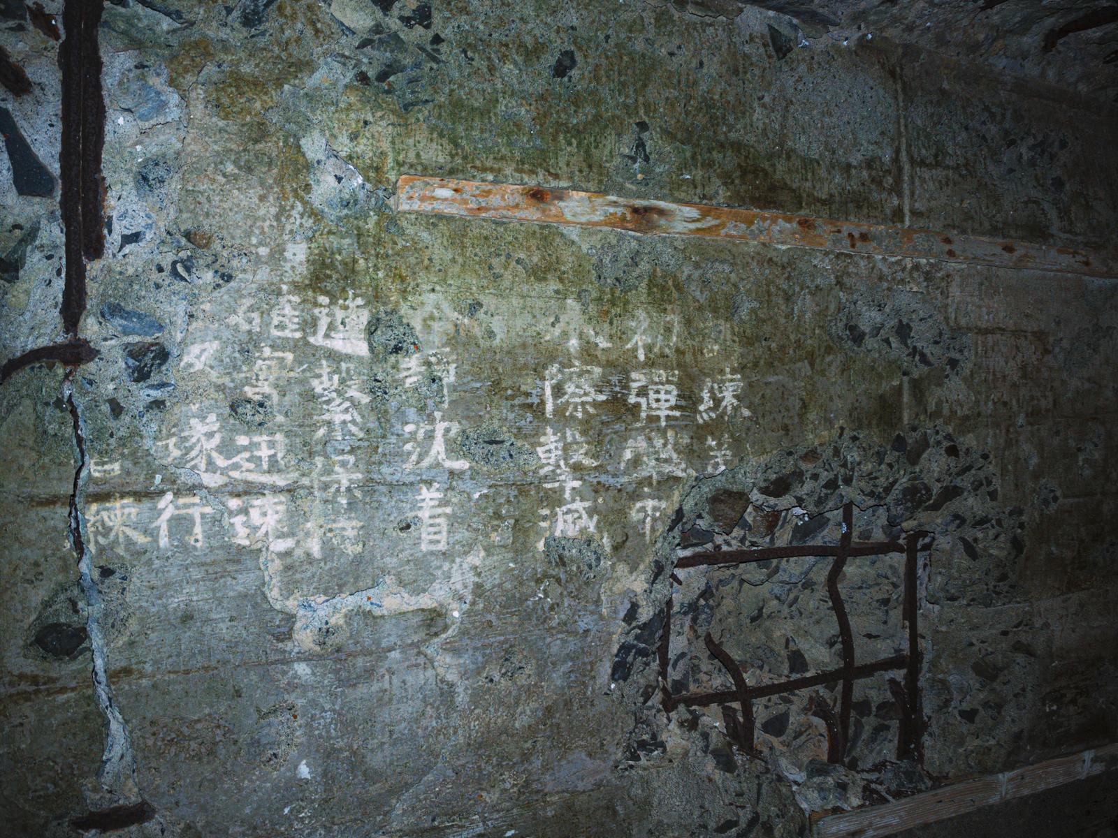 硫黄島の砲台跡に残された漢字の刻まれたコンクリート壁と苔や錆