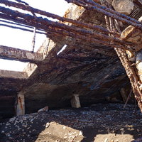 砂浜に横たわる朽ちた船内に入り込む砂の上にちらばる細かく砕け剥がれた欠片の写真