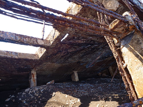 砂浜に横たわる朽ちた船内に入り込む砂の上にちらばる細かく砕け剥がれた欠片