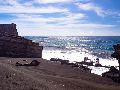 瓦礫が散らばる浜辺に寄せて白く泡立つ波