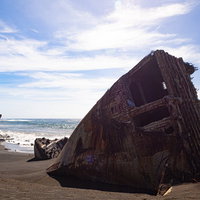 千鳥ヶ浜の波打ち際に横たわる船の瓦礫と続く白波の写真