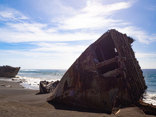 千鳥ヶ浜の波打ち際に横たわる船の瓦礫と続く白波