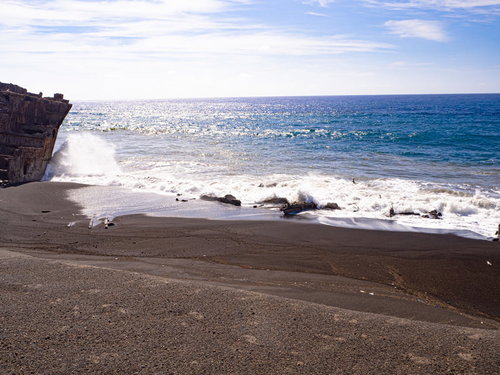 千鳥ヶ浜の白い砂浜と瓦礫に打ち寄せる青い波