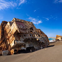 海底隆起によって海の底から姿を現し再び南国の光に焼かれる船の残骸の写真