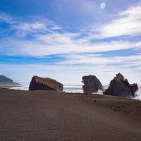 千鳥ヶ浜の沈船群にぶつかり砕ける波と遠くに見える摺鉢山の写真