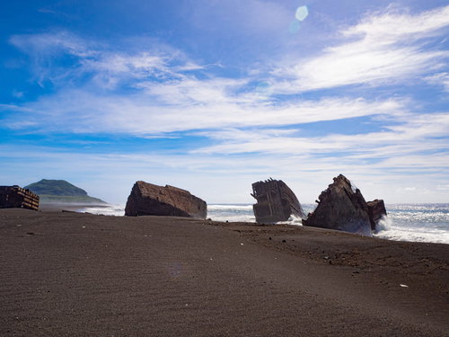 千鳥ヶ浜の沈船群にぶつかり砕ける波と遠くに見える摺鉢山