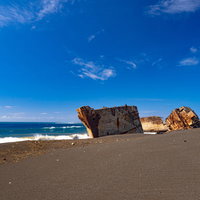 美しい青空と青い海の中で砂浜に横たわる米軍が港湾整備のために沈めた船の残骸の写真