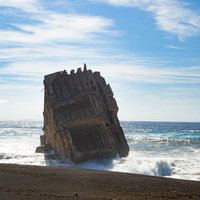 白く輝く砕ける波の中に立つ船の残骸の写真