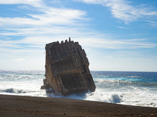 白く輝く砕ける波の中に立つ船の残骸