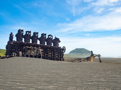 千鳥ヶ浜に聳え立つ錆びついた船のエンジンと向うに見える摺鉢山