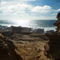 激しく寄せる波の飛沫でかすむ釜岩の波打ち際の写真