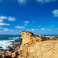▲青空と青い海に向かって特徴ある姿でそそり立つ釜岩の奇岩の写真