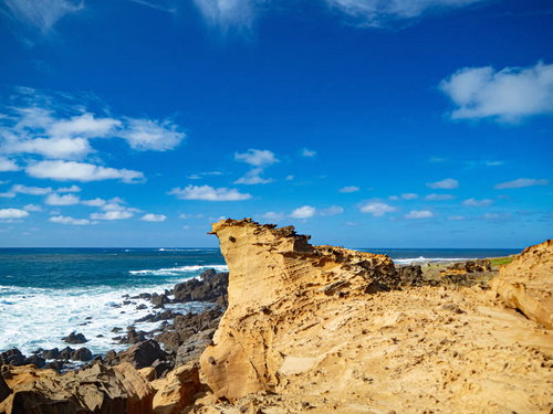 ▲青空と青い海に向かって特徴ある姿でそそり立つ釜岩の奇岩の写真