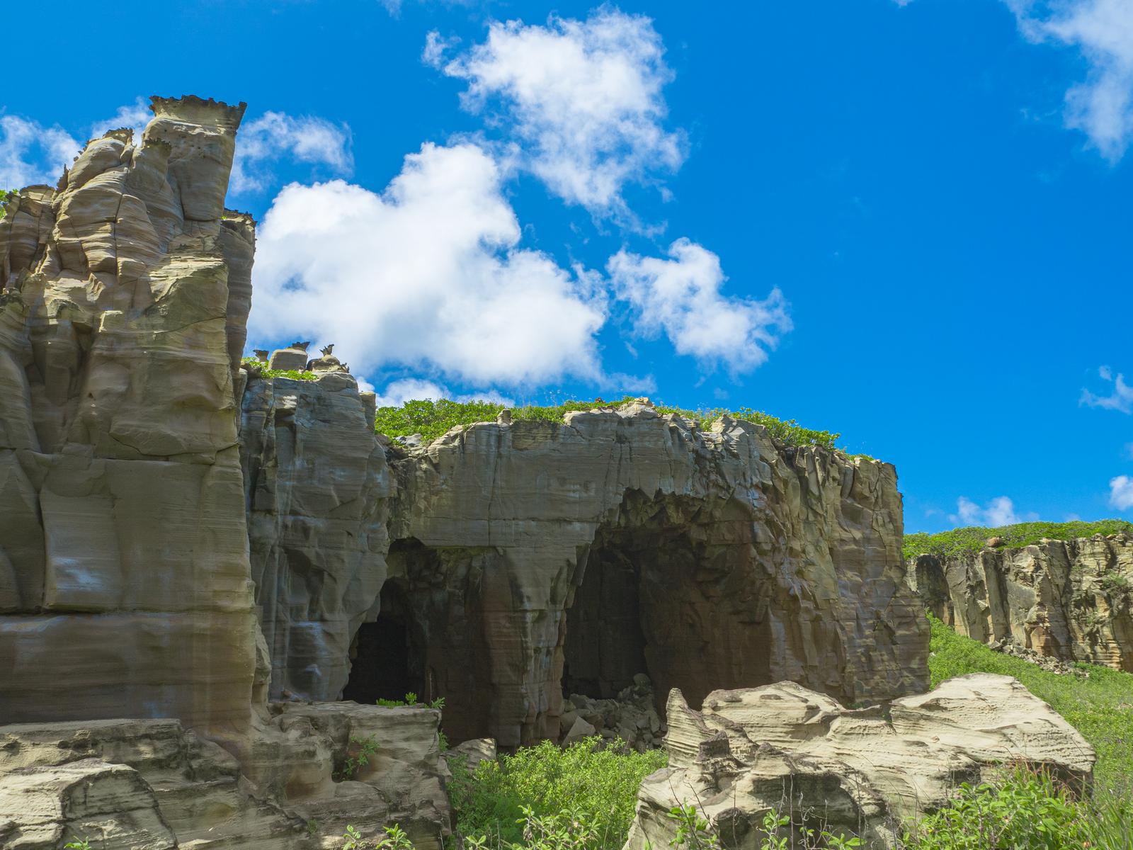硫黄島の神山海岸の崖に空いた大きな岩の洞穴と青空