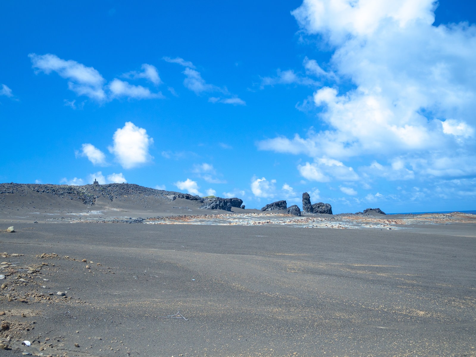 硫黄島の日出浜から遠くの丘上に立つ西大佐の碑を望む風景