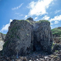 硫黄島唯一の真水が溜まる高さ１０メートルほどの柱状節理が集まった大きな岩山の写真