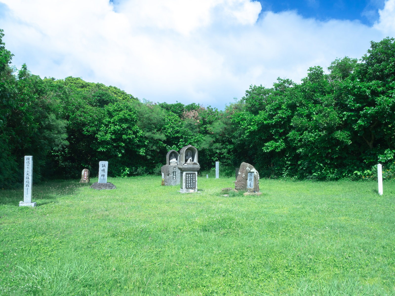 青空の下の緑の草原に立つ硫黄島北観音の石碑群