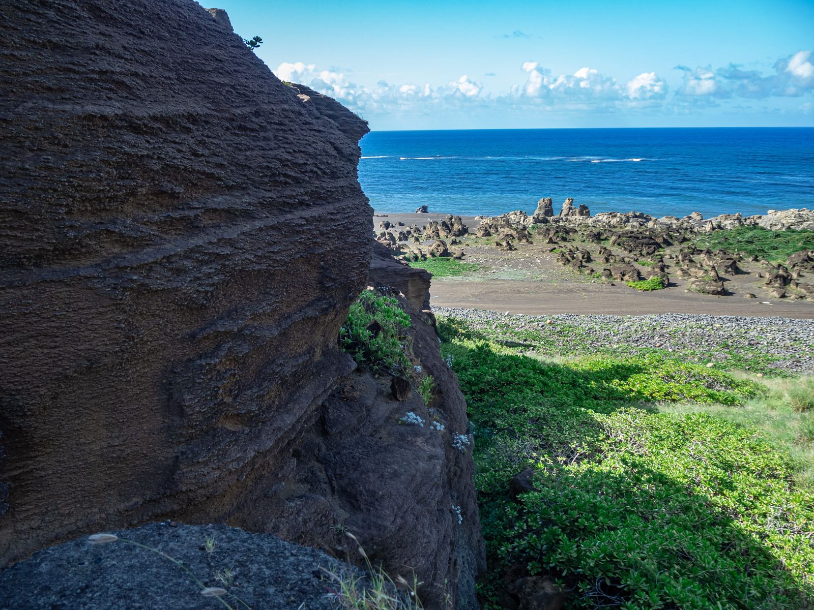 北の鼻の浜へと向かう岩壁沿いの道と青い海の風景