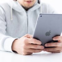 両手でiPad miniを操作する男性の写真