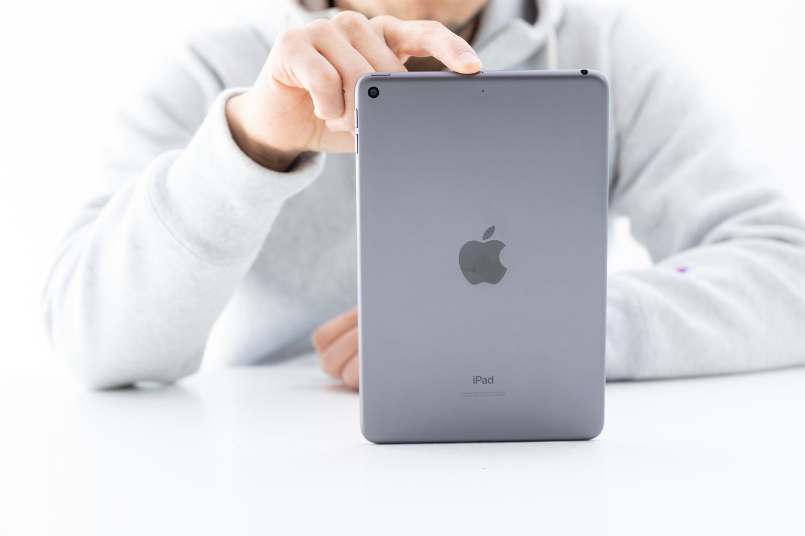 iPad miniの裏面を一本指で持つ男性［モデル：g.O.R.i］