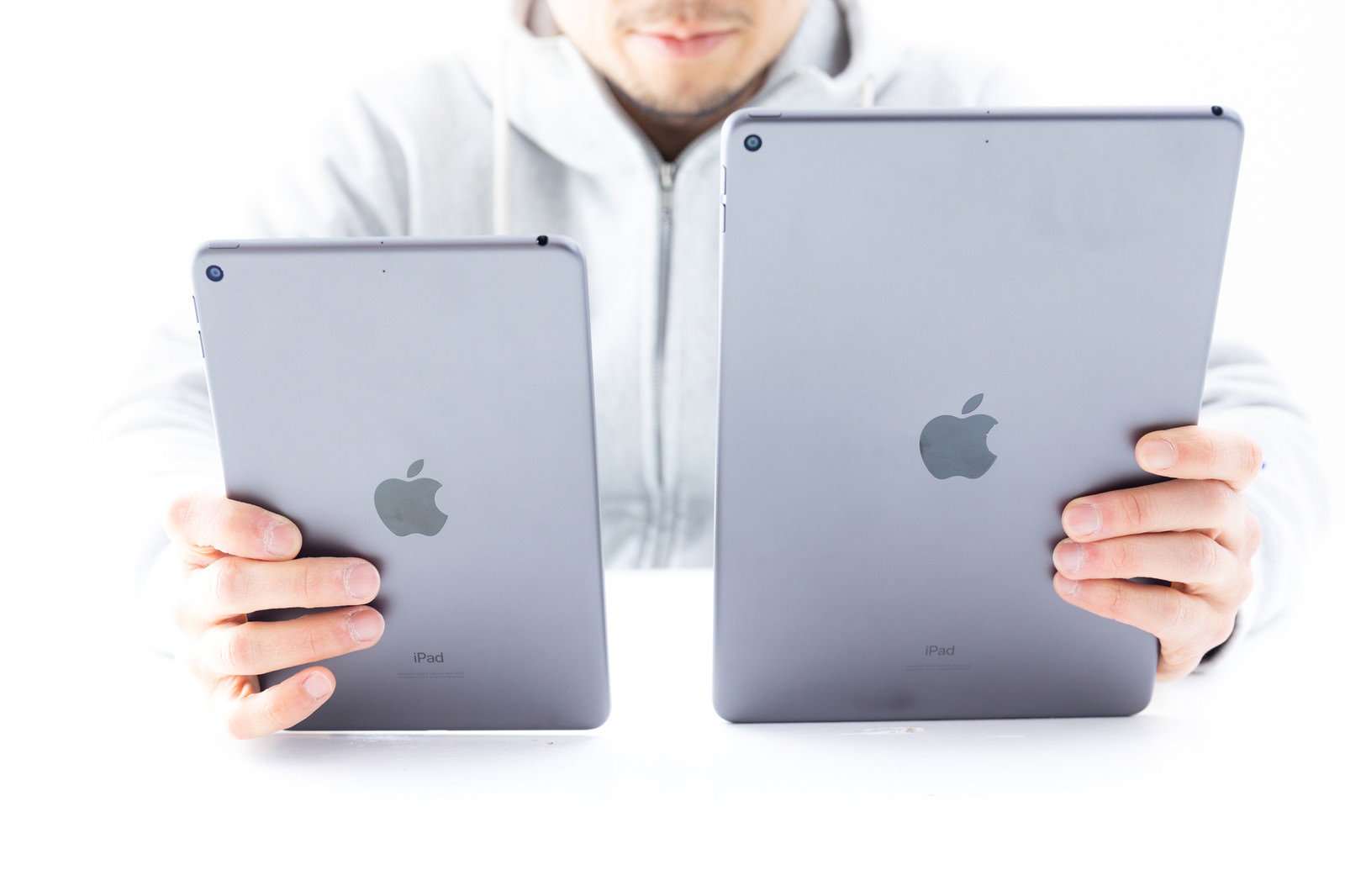 2台のiPadを両手に持って比べる男性