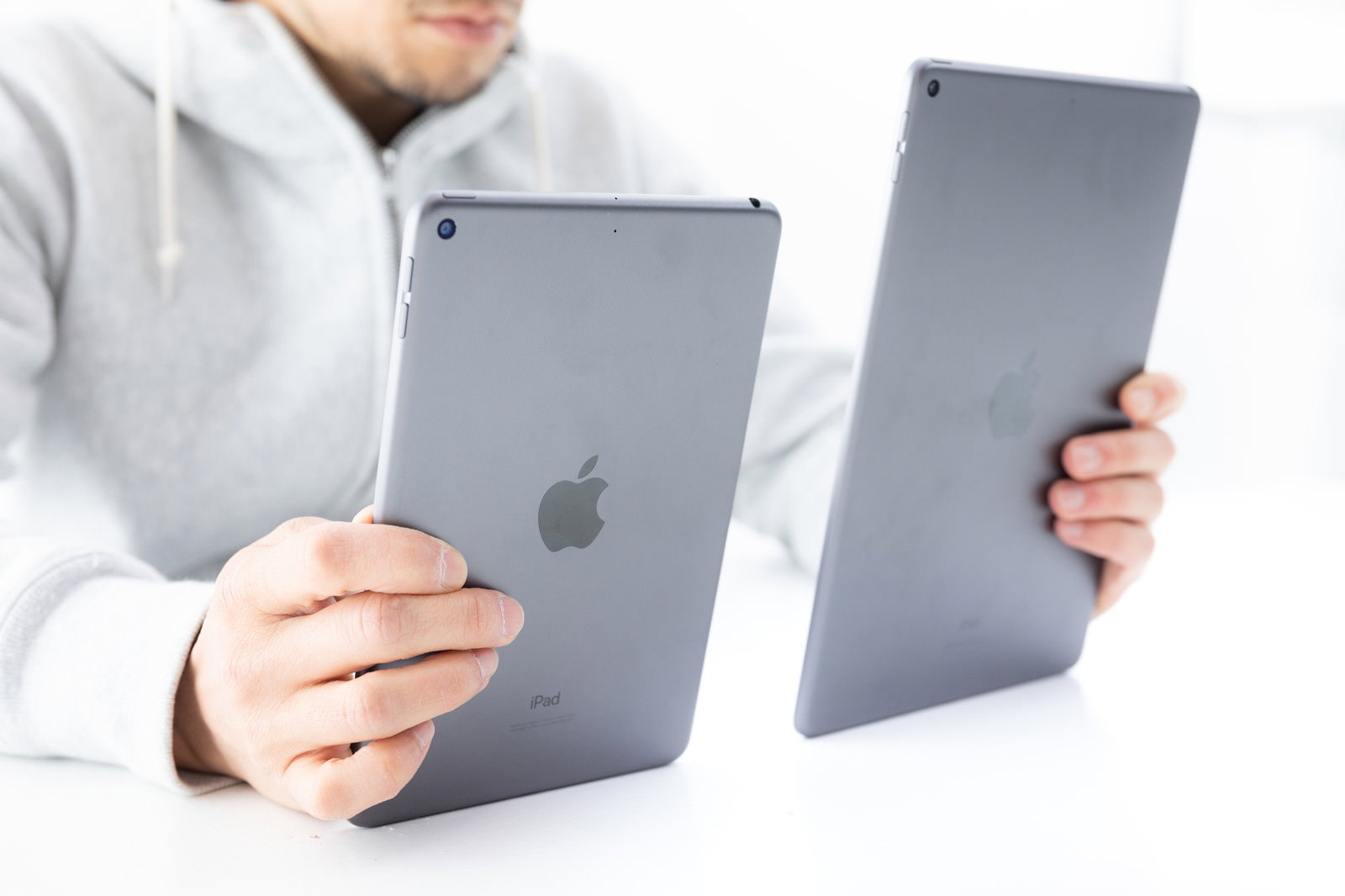 男性が2台のiPad miniを裏面向きで持ち比べている