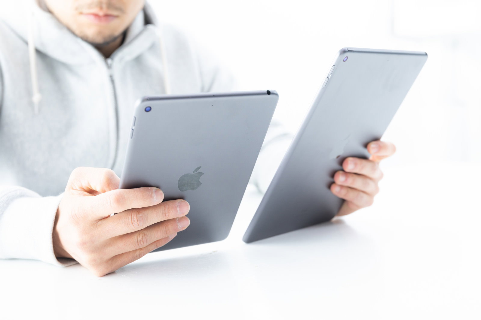 2台のiPadを両手で持ち見比べる男性