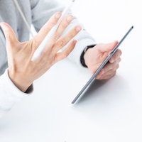 タブレットを手に持って操作する男性の手元の写真