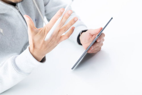 タブレットを手に持って操作する男性の手元