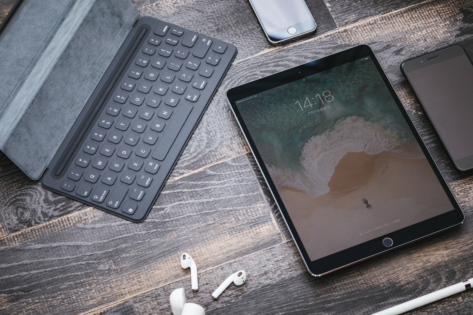 木目調のテーブルに置かれたタブレット端末とiPhone、Apple Pencil