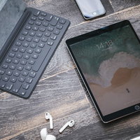 木目の床に置かれたタブレット端末とiPhoneの写真