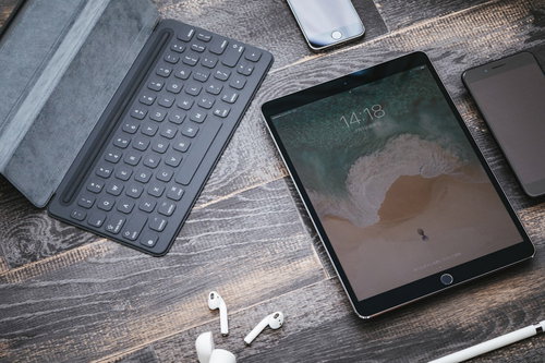 木目の床に置かれたタブレット端末とiPhone